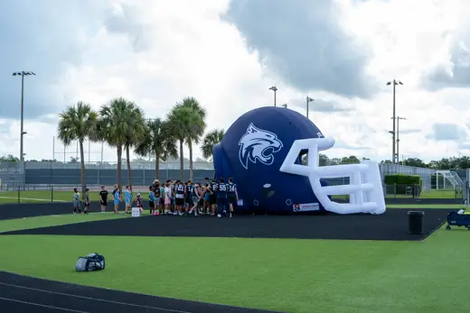 The Bobcats' giant inflatable helmet on the field with campers lined up at 2026 training camp