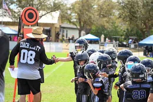 Coach high-fiving the line of Bobcats players