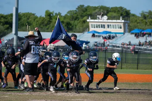 Bobcats waving the team flag over the huddle before kickoff